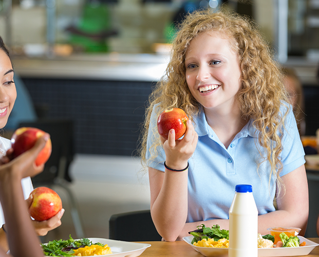 Smiling woman with healthy teeth holding red apple.