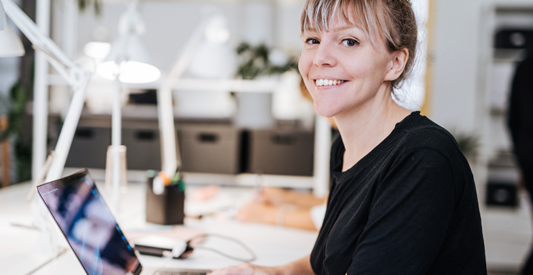 Lady is looking at camera and smiling while working in office