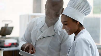 Two chefs discuss while using tablet computer