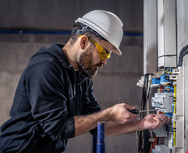 a-male-electrician-works-in-a-switchboard-with-an-electrical-connecting-cable