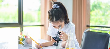 little scientist looking through microscope test