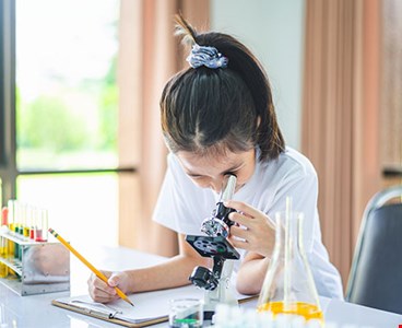 little scientist looking through microscope test