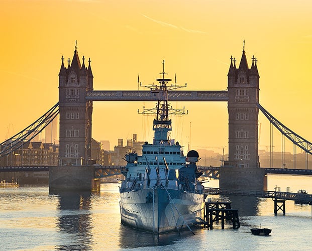 HMS belfast moored in front of tower bridge sunrise in London