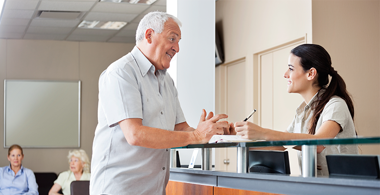 Man discussing with lady receptionist at hospital billing counter