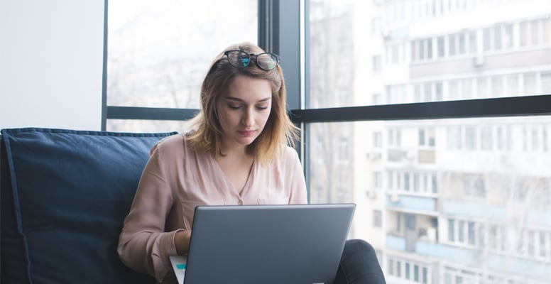 A girl sits on a sofa at the window in a modern office