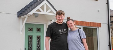 Happy couple standing in front of house