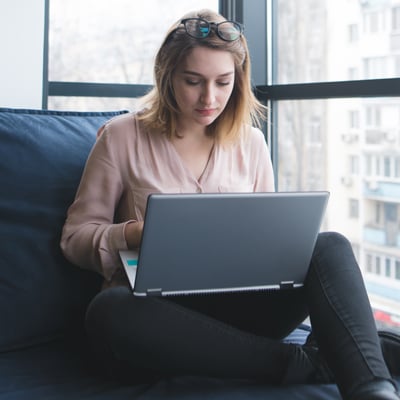 A girl sits on a sofa at the window in a modern office