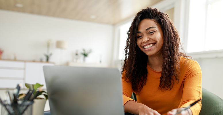 distance-education-portrait-of-smiling-woman-sitting-at-desk-using-laptop-and-writing-in-notebook.png