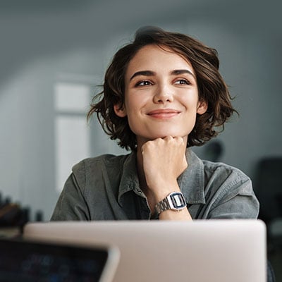 Image of joyful woman smiling while working with laptop