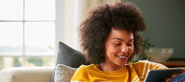 Curly hair girl with tablet on sofa